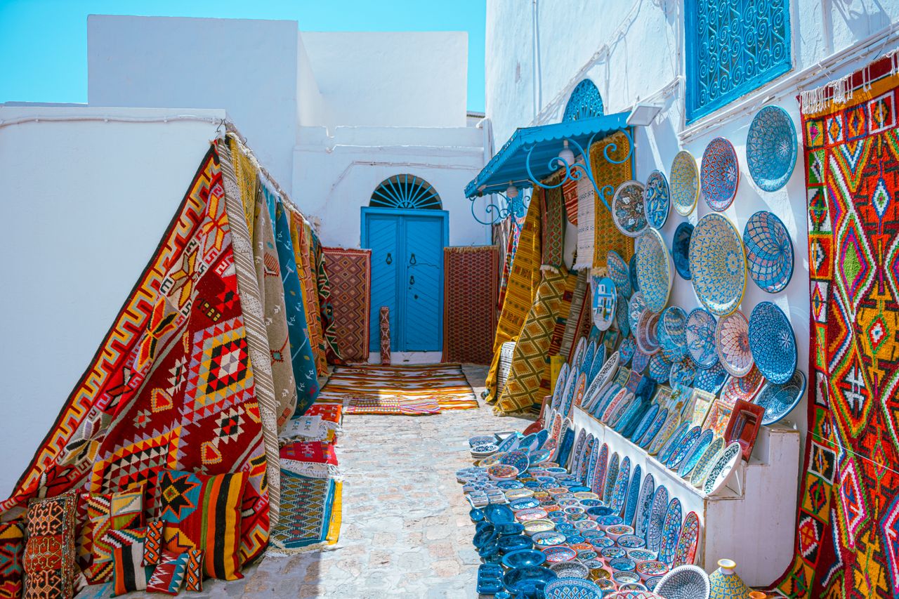 Vibrant display of traditional Tunisian carpets and pottery in Carthage market.