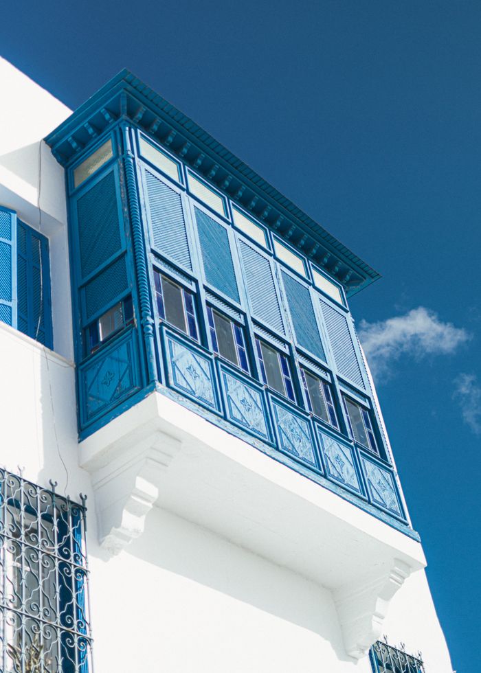 A vibrant blue traditional balcony in Carthage, Tunisia under a clear blue sky.